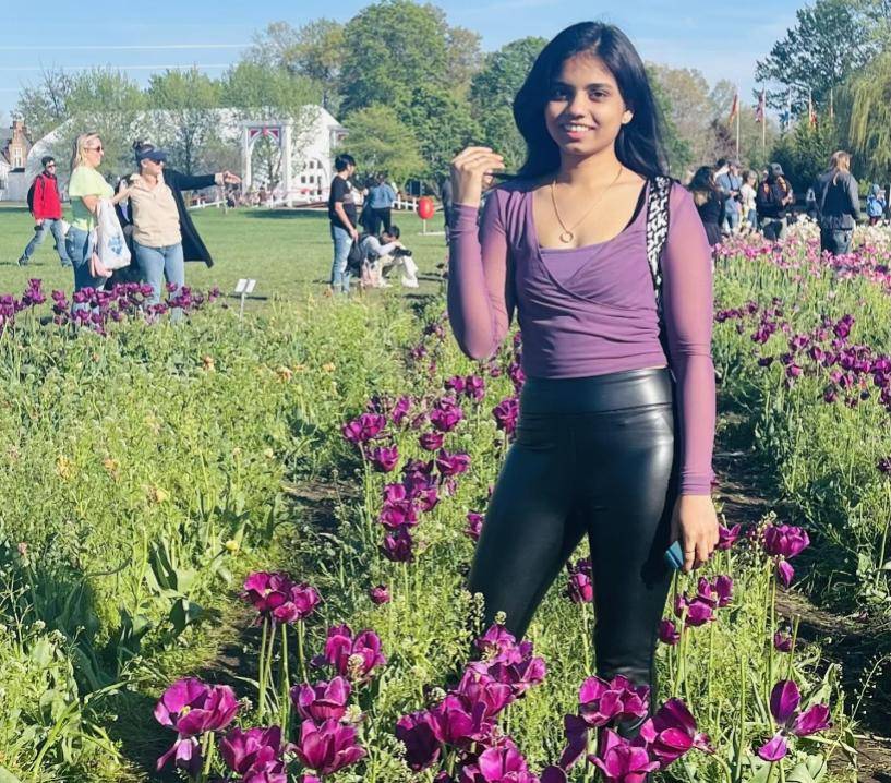 Woman smiling at camera, standing amongst purple tulips